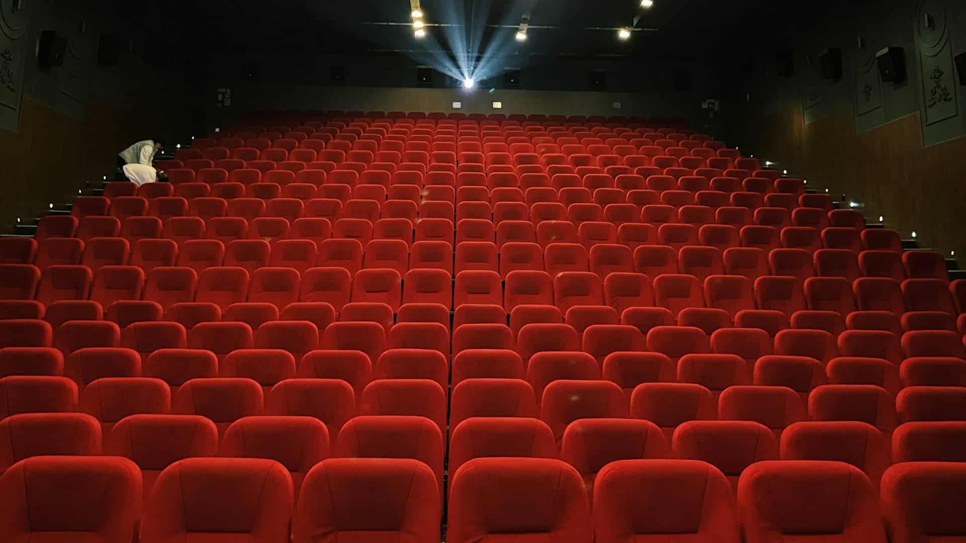 A large hall of red seats, crossed by the projector beam