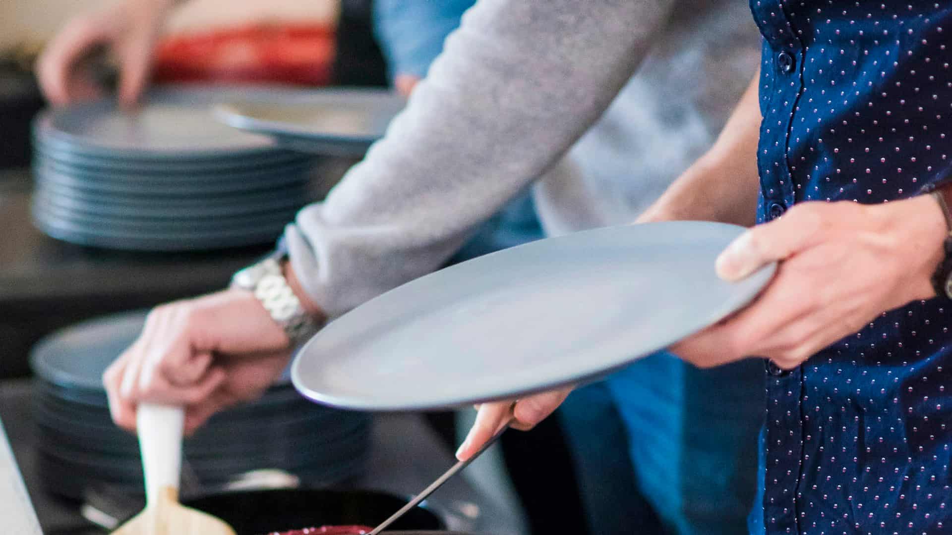 Handen die borden aangeven boven een stapel borden