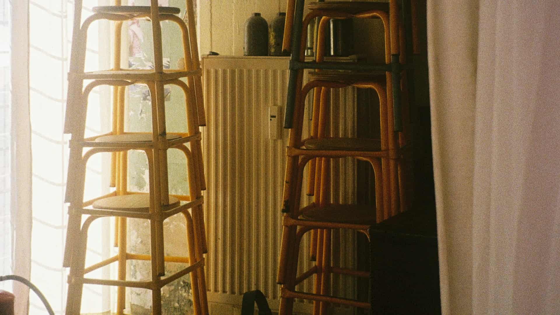 Dos pilas de taburetes de ratán recogidas junto a una ventana